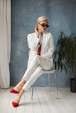Beautiful Young Woman With Perfect Blond Hair In Elegant White Suit And Red Shoes Posing In Studio. Fashionable Blonde Royalty Free Stock Photography