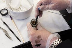 Beauty brows care concept: master is mixing henna for eyebrows coloring. swatches on hand in glove stock photo Beauty brows care concept: master is mixing henna for eyebrows coloring. swatches on hand in glove stock photo
