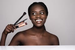 Beauty Portrait Of A Smiling Beautiful Half Naked African Woman Posing With Make-up Brushes And Looking Away Isolated Over White Stock Images Beauty Portrait Of A Smiling Beautiful Half Naked African Woman Posing With Make-up Brushes And Looking Away Isolated Over White Stock Images