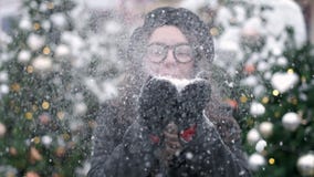 SLOW MOTION: Young woman blowing snow. Young woman blowing snow. Portrait of cute young woman blowing on snow in her stock footage SLOW MOTION: Young woman blowing snow. Young woman blowing snow. Portrait of cute young woman blowing on snow in her stock footage