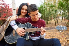 Beaux couples dans l'amour sur la nature avec une guitare images stock Beaux couples dans l'amour sur la nature avec une guitare images stock