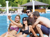Beaux jeunes amis riant et faisant le selfie sur la piscine image stock Beaux jeunes amis riant et faisant le selfie sur la piscine image stock