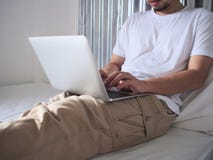 Bebouwd beeld van het jonge Aziatische mens typen op computerlaptop op het bed Internet van dingenconcept stock foto's Bebouwd beeld van het jonge Aziatische mens typen op computerlaptop op het bed Internet van dingenconcept stock foto's
