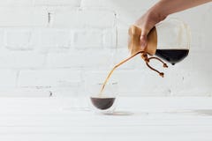Bebouwd schot die van vrouw alternatieve koffie van chemex gieten in glasmok stock foto's Bebouwd schot die van vrouw alternatieve koffie van chemex gieten in glasmok stock foto's