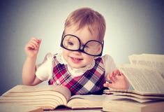 Bebê engraçado nos vidros que lê um livro fotografia de stock Bebê engraçado nos vidros que lê um livro fotografia de stock