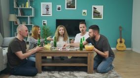 Bedrijf van jongens en meisjes die raadsspel in woonkamer spelen en bier drinken stock footage Bedrijf van jongens en meisjes die raadsspel in woonkamer spelen en bier drinken stock footage