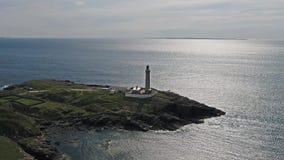 Bedöva antennskottet av den Ardnamurchan fyren med de härliga vitstränderna och costlinen i bakgrunden stock video Bedöva antennskottet av den Ardnamurchan fyren med de härliga vitstränderna och costlinen i bakgrunden stock video