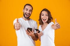 Beeld van de tevreden paarmens en vrouw die terwijl allebei die mobiele die telefoons met behulp van glimlachen, over gele achter royalty-vrije stock afbeelding Beeld van de tevreden paarmens en vrouw die terwijl allebei die mobiele die telefoons met behulp van glimlachen, over gele achter royalty-vrije stock afbeelding