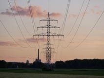 Beeld van machtslijn tijdens zonsondergang met elektrische centrale stock fotografie Beeld van machtslijn tijdens zonsondergang met elektrische centrale stock fotografie