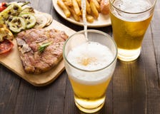 Beer being poured into glass with gourmet steak and french fries stock photos Beer being poured into glass with gourmet steak and french fries stock photos