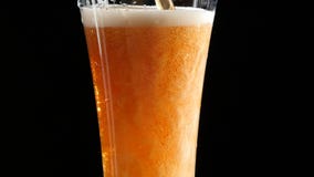 Beer is pouring into a glass on black background.