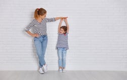 Begrepp av familjen modern mäter tillväxt av barnet till daught royaltyfri fotografi Begrepp av familjen modern mäter tillväxt av barnet till daught royaltyfri fotografi