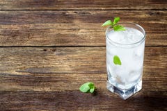 Begreppsmeny för drinkar - förnyande dryck med mintkaramellen och is i ett exponeringsglas på en trälantlig tabell arkivfoton Begreppsmeny för drinkar - förnyande dryck med mintkaramellen och is i ett exponeringsglas på en trälantlig tabell arkivfoton
