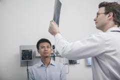 Behandeln Sie das Halten und das Betrachten des Röntgenstrahls des Patienten stockbild Behandeln Sie das Halten und das Betrachten des Röntgenstrahls des Patienten stockbild
