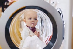 Behandla som ett barn ser till och med fönstret av tvagningmaskinen royaltyfria bilder Behandla som ett barn ser till och med fönstret av tvagningmaskinen royaltyfria bilder