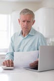 Bekymrad mogen man med beräknande hushållfinanser för bärbar dator arkivfoton Bekymrad mogen man med beräknande hushållfinanser för bärbar dator arkivfoton