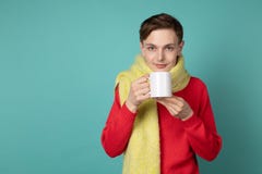 Bel homme sensuel utilisant le chandail rouge et l'?charpe, tenant la tasse de th? ? disposition images libres de droits Bel homme sensuel utilisant le chandail rouge et l'?charpe, tenant la tasse de th? ? disposition images libres de droits