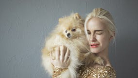 Bella donna bionda con il suo Spitz isolato su Grey stock footage Bella donna bionda con il suo Spitz isolato su Grey stock footage