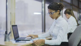 Bella donna biraziale che confronta i grafici finanziari, femmina lavorante dura, ufficio stock footage Bella donna biraziale che confronta i grafici finanziari, femmina lavorante dura, ufficio stock footage