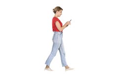 Bella giovane donna che cammina e che legge messaggio di testo sul suo telefono cellulare su fondo bianco fotografia stock libera da diritti Bella giovane donna che cammina e che legge messaggio di testo sul suo telefono cellulare su fondo bianco fotografia stock libera da diritti