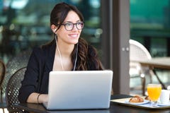 Bella giovane donna che sembra obliqua mentre lavorando con il suo computer portatile in una caffetteria fotografia stock libera da diritti Bella giovane donna che sembra obliqua mentre lavorando con il suo computer portatile in una caffetteria fotografia stock libera da diritti