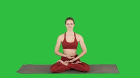 Bella giovane donna che si siede nella posizione cambiante di Lotus di posa di yoga delle sue mani su uno schermo verde, chiave d stock footage Bella giovane donna che si siede nella posizione cambiante di Lotus di posa di yoga delle sue mani su uno schermo verde, chiave d stock footage