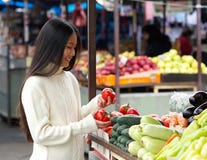Bella giovane donna che sorride al mercato di verdure fotografia stock Bella giovane donna che sorride al mercato di verdure fotografia stock