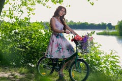 Bella giovane donna in un vestito ed in un cappello su una bicicletta sul nazionale Immagine Stock Bella giovane donna in un vestito ed in un cappello su una bicicletta sul nazionale Immagine Stock