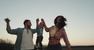 Bella giovane famiglia sorridente, tre membri, papà della mamma e la loro camminata felice del figlio del bambino attraverso il c video d archivio Bella giovane famiglia sorridente, tre membri, papà della mamma e la loro camminata felice del figlio del bambino attraverso il c video d archivio