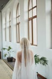 Bella giovane sposa in un vestito da sposa ed in un velo bianchi, stanti nell'hotel ed aspettanti lo sposo prima del ceremo di no fotografia stock libera da diritti Bella giovane sposa in un vestito da sposa ed in un velo bianchi, stanti nell'hotel ed aspettanti lo sposo prima del ceremo di no fotografia stock libera da diritti
