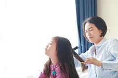 Bella piccola ragazza asiatica del bambino con capelli lunghi e la mamma agghindati per capelli lisci alla mattina nella stanza fotografie stock Bella piccola ragazza asiatica del bambino con capelli lunghi e la mamma agghindati per capelli lisci alla mattina nella stanza fotografie stock