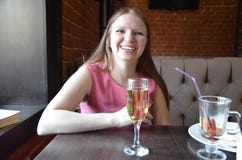 Bella ragazza bionda che tiene un vetro di champagne o di vino, champagne bevente in un ristorante, in un vestito rosa uguagliant immagine stock Bella ragazza bionda che tiene un vetro di champagne o di vino, champagne bevente in un ristorante, in un vestito rosa uguagliant immagine stock