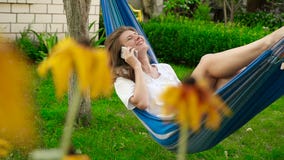 Bella ragazza che si trova in un'amaca Sta parlando sul telefono e sulla risata HD stock footage Bella ragazza che si trova in un'amaca Sta parlando sul telefono e sulla risata HD stock footage