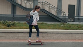Bella ragazza con il longboard di guida dello zaino nello studente soleggiato di skateboarding del pattinatore del pattino del te stock footage Bella ragazza con il longboard di guida dello zaino nello studente soleggiato di skateboarding del pattinatore del pattino del te stock footage
