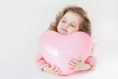 Bella ragazza prescolare in uno studio bianco con i palloni in forma di cuore rosa fotografia stock Bella ragazza prescolare in uno studio bianco con i palloni in forma di cuore rosa fotografia stock