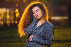 Bella ragazza sorridente con riccio, capelli illuminati dal sole fotografia stock Bella ragazza sorridente con riccio, capelli illuminati dal sole fotografia stock