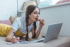 bella scrittura teenager del biscotto di cibo della ragazza nel quaderno e per mezzo del computer portatile fotografie stock bella scrittura teenager del biscotto di cibo della ragazza nel quaderno e per mezzo del computer portatile fotografie stock