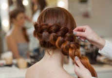 Belle, avec longtemps, la fille velue rousse, coiffeuse tisse une tresse française, plan rapproché dans un salon de beauté photos libres de droits Belle, avec longtemps, la fille velue rousse, coiffeuse tisse une tresse française, plan rapproché dans un salon de beauté photos libres de droits
