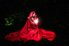 Belle femme avec le manteau et la lanterne rouges dans les bois photos stock Belle femme avec le manteau et la lanterne rouges dans les bois photos stock