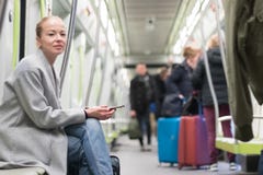 Belle femme blonde à l'aide du téléphone intelligent tout en voyageant par transport en commun de métro photographie stock libre de droits Belle femme blonde à l'aide du téléphone intelligent tout en voyageant par transport en commun de métro photographie stock libre de droits