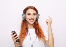Belle femme de redhair dans des écouteurs écoutant la musique photos stock Belle femme de redhair dans des écouteurs écoutant la musique photos stock