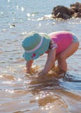 Belle fille avec le maillot de bain et le chapeau jouant sur la rive avec de l'eau image libre de droits Belle fille avec le maillot de bain et le chapeau jouant sur la rive avec de l'eau image libre de droits