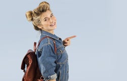 Belle fille d'étudiant dans une veste de denim avec un sac à dos sur ses épaules dans le studio sur un fond bleu Le concept de image libre de droits Belle fille d'étudiant dans une veste de denim avec un sac à dos sur ses épaules dans le studio sur un fond bleu Le concept de image libre de droits