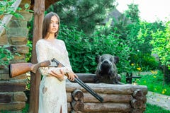 Belle fille dans la robe blanche posant avec un fusil de chasse photographie stock Belle fille dans la robe blanche posant avec un fusil de chasse photographie stock