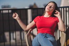 Belle fille dans un T-shirt rouge et des écouteurs Une fille sur le balcon écoutant la musique et chante Photo stock Belle fille dans un T-shirt rouge et des écouteurs Une fille sur le balcon écoutant la musique et chante Photo stock