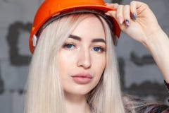 Belle fille la blonde d'agent de maîtrise de concepteur dans un casque orange de construction et des combinaisons de jeans Concep photographie stock libre de droits Belle fille la blonde d'agent de maîtrise de concepteur dans un casque orange de construction et des combinaisons de jeans Concep photographie stock libre de droits
