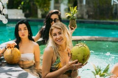 belle giovani donne in swimwear che tiene frutti tropicali ed i cocktail fotografia stock libera da diritti belle giovani donne in swimwear che tiene frutti tropicali ed i cocktail fotografia stock libera da diritti