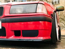 Belle grandi ruote di corsa di un'automobile rossa di sport con uno spazio al suolo molto basso sulle ruote costose brillanti fus immagini stock libere da diritti Belle grandi ruote di corsa di un'automobile rossa di sport con uno spazio al suolo molto basso sulle ruote costose brillanti fus immagini stock libere da diritti