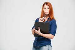 Belle jeune femme rousse songeuse tenant le presse-papiers et la pensée Photographie stock libre de droits Belle jeune femme rousse songeuse tenant le presse-papiers et la pensée Photographie stock libre de droits