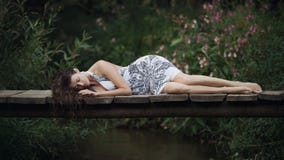 Belle jeune femme se trouvant sur le pont au-dessus de la rivière de forêt photos stock Belle jeune femme se trouvant sur le pont au-dessus de la rivière de forêt photos stock